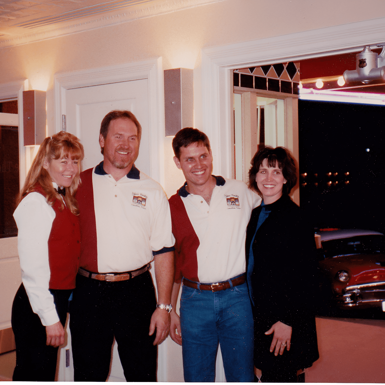 Four people smiling indoors near doorway.