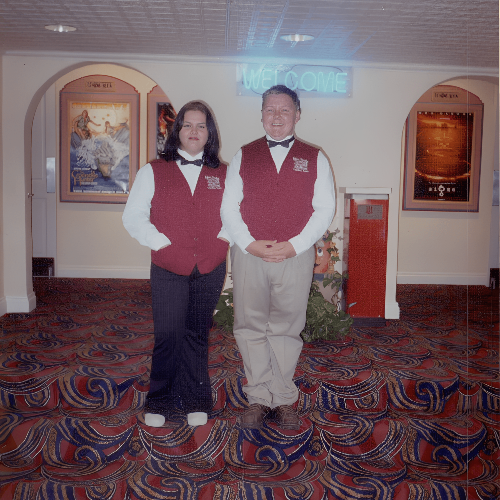 Two ushers in red vests smiling.