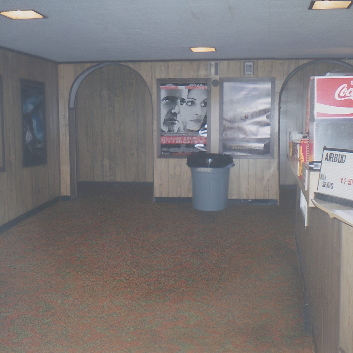 Vintage movie theater lobby with posters displayed.