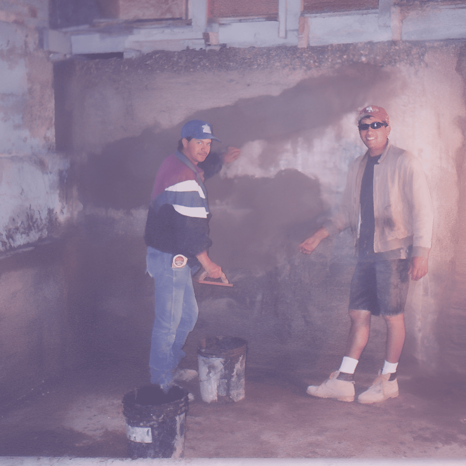 Two men painting a concrete wall together.