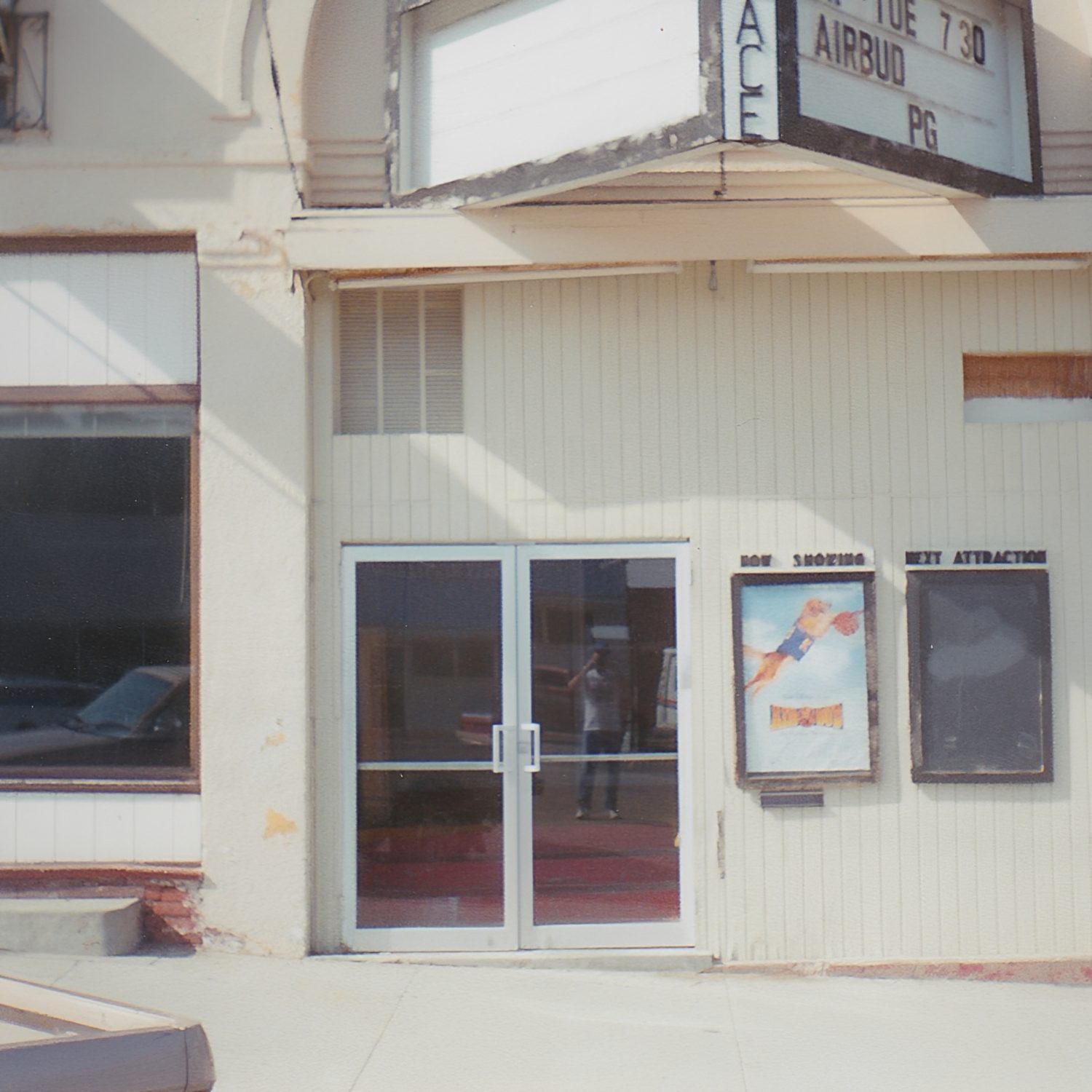 Old theater entrance with movie poster display.